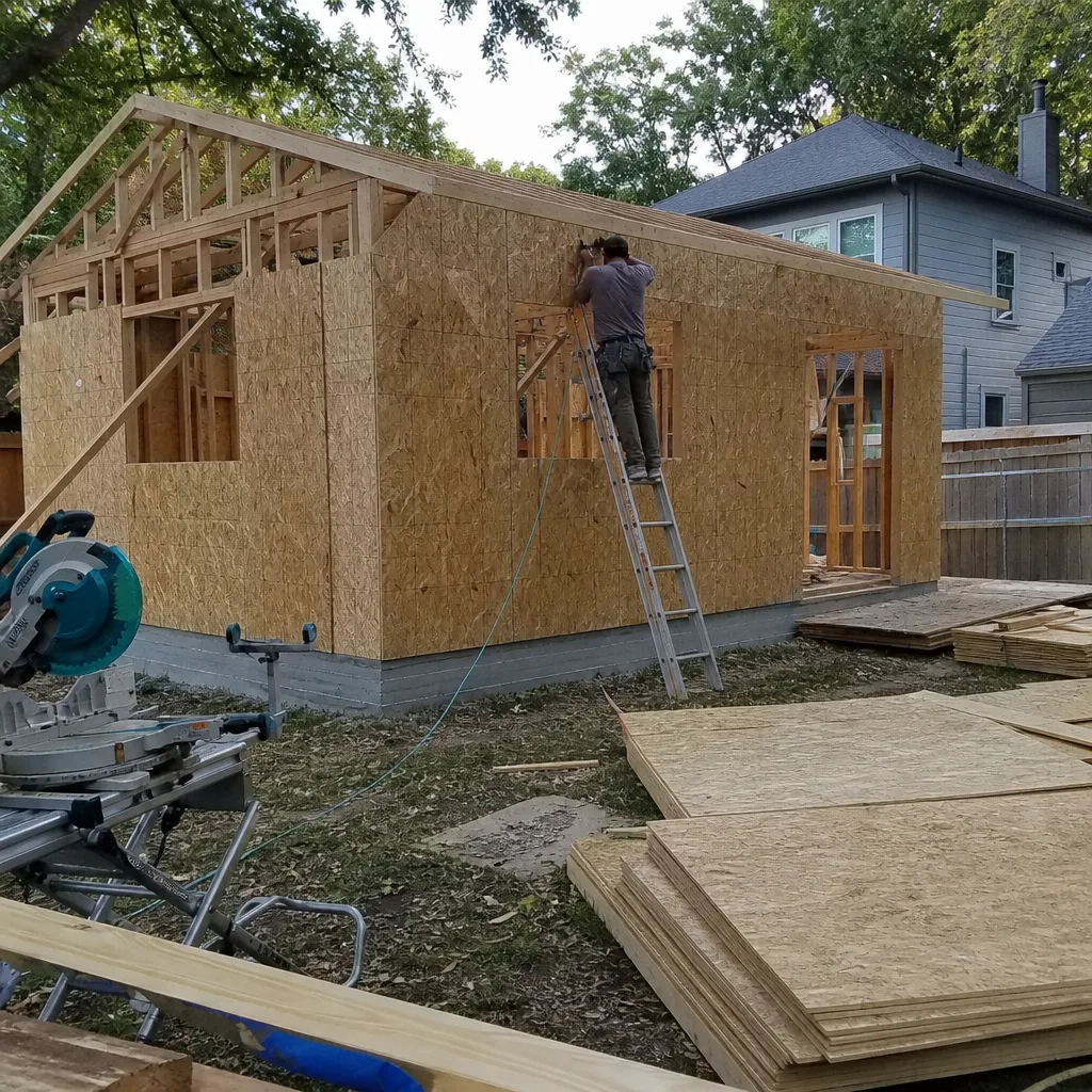 Contractor installing exterior wall sheathing on a backyard room addition project